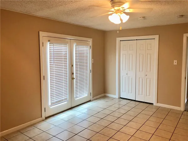 an empty room with windows and ceiling fan