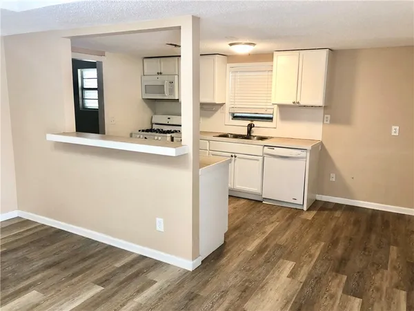 a kitchen with stainless steel appliances granite countertop a stove a sink and white cabinets with wooden floor
