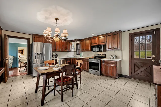 a kitchen with stainless steel appliances granite countertop a stove top oven a sink dishwasher a dining table and chairs with wooden floor