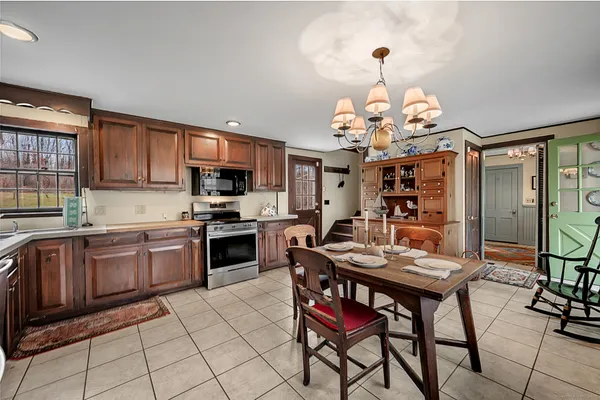 a kitchen with stainless steel appliances granite countertop a stove top oven a sink dishwasher a dining table and chairs with wooden floor