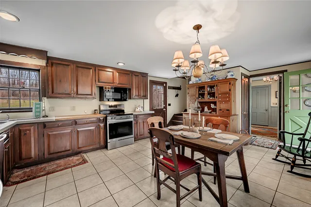 a kitchen with stainless steel appliances granite countertop a stove top oven a sink dishwasher a dining table and chairs with wooden floor