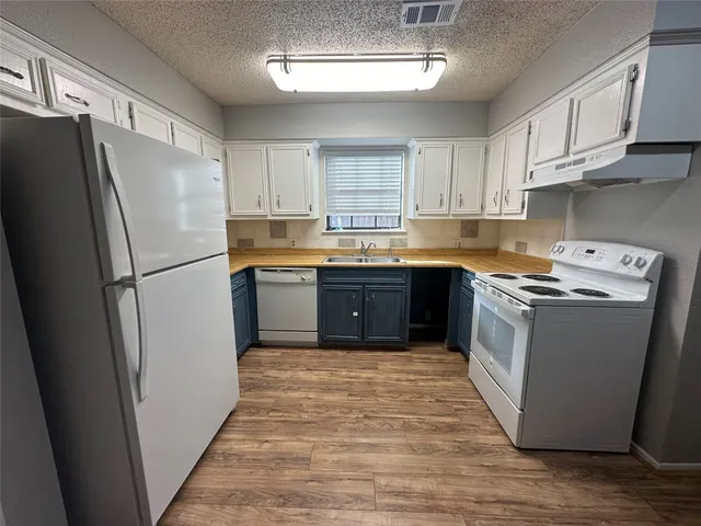 a kitchen with granite countertop a refrigerator stove top oven and sink