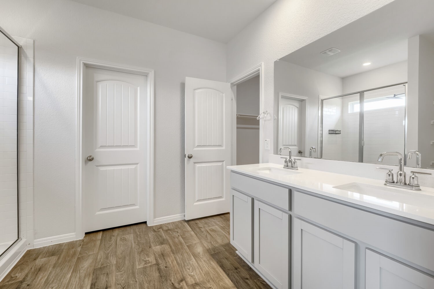 13507 Howser Trace Manor, TX 78653 - Photo 12 of 28 Double vanity with sleek white countertops and a spacious walk-in shower elevate this bathroom.