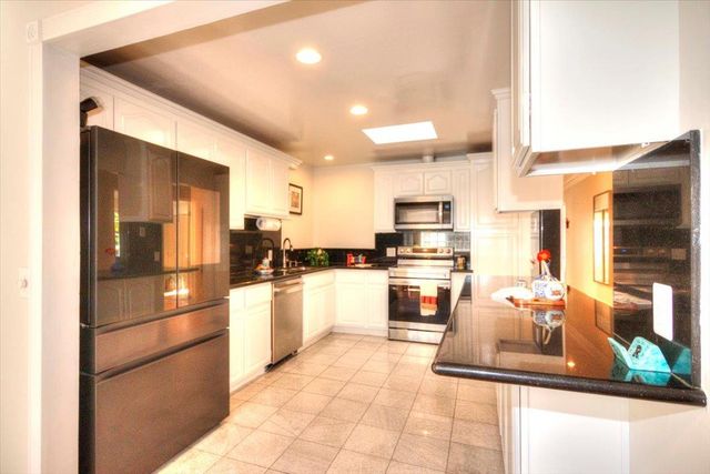 a kitchen with stainless steel appliances granite countertop a refrigerator and a stove top oven