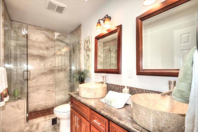a bathroom with a granite countertop sink and mirror with bathtub