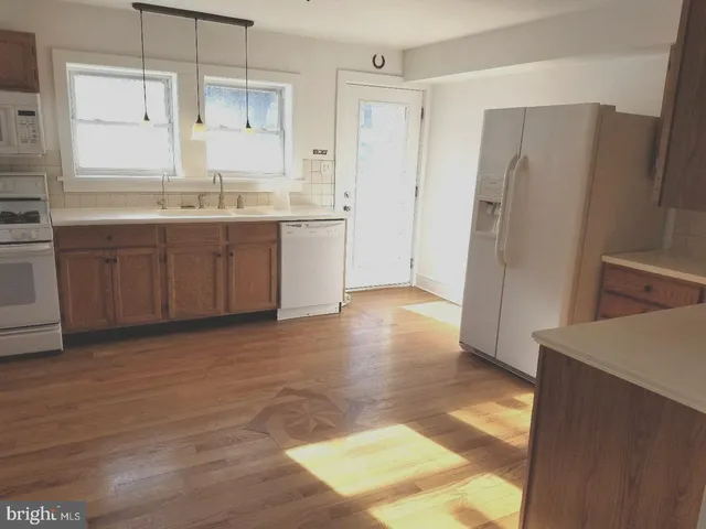 a view of a kitchen with a sink a refrigerator and wooden floor