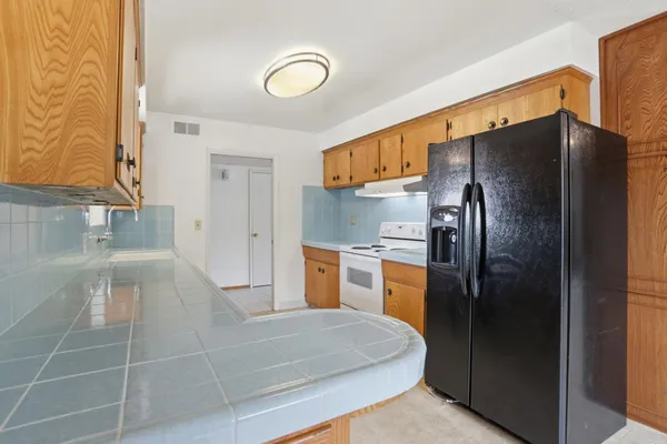 a kitchen with stainless steel appliances granite countertop a refrigerator a stove and a sink