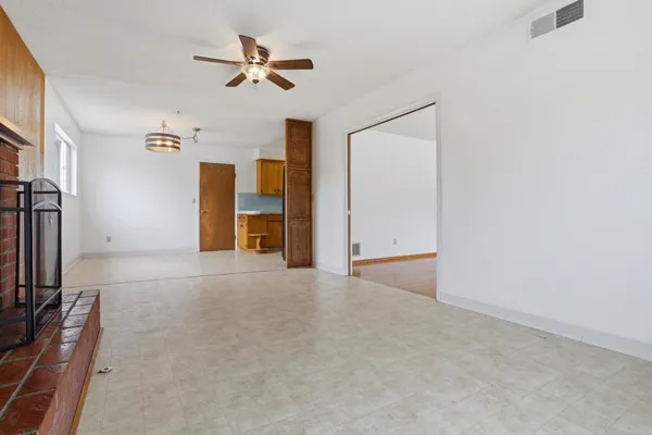 an empty room with ceiling fan and window