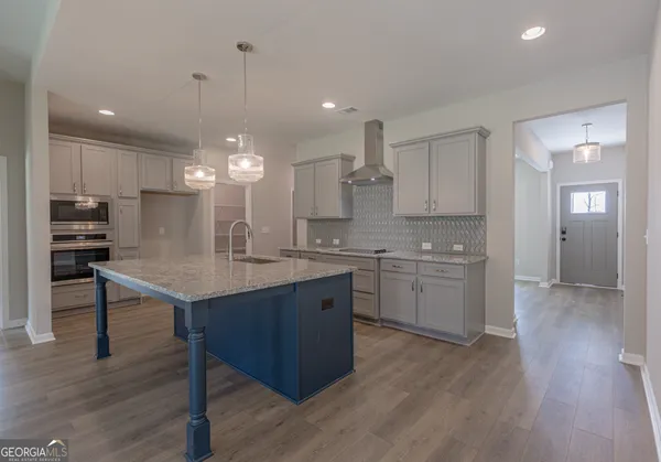 a kitchen with kitchen island granite countertop a sink cabinets and wooden floor