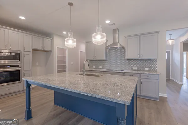 a kitchen with kitchen island granite countertop a sink cabinets and stainless steel appliances