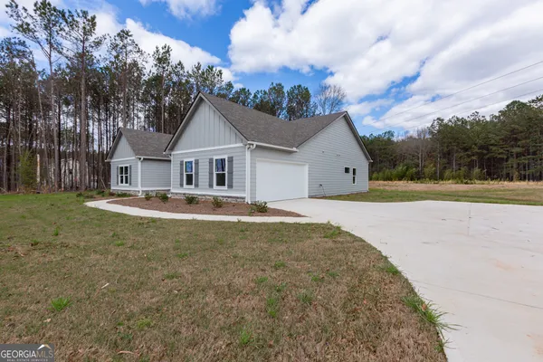 a front view of a house with a garden and trees