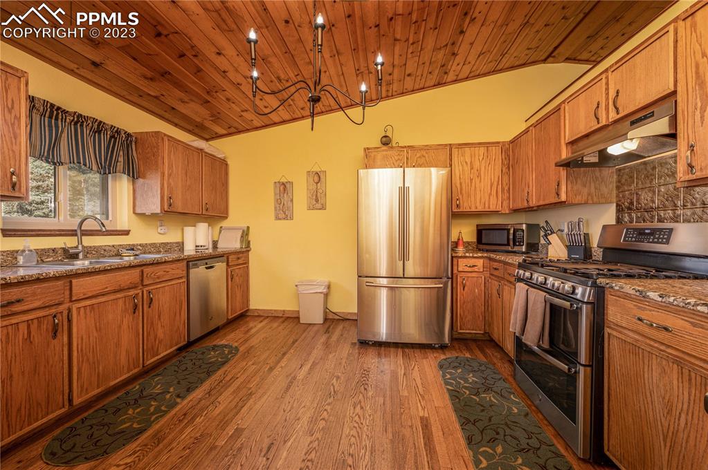 1313 Spring Valley Drive Divide, CO 80814 - Photo 5 of 25 a kitchen with stainless steel appliances granite countertop a refrigerator a sink dishwasher a stove with wooden cabinets and floor