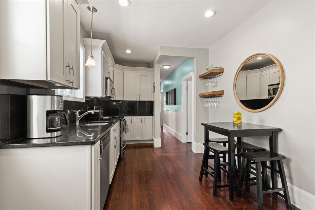 573 Bennington Street, Unit 2 Boston, MA 02128 - Photo 11 of 22 a kitchen with stainless steel appliances granite countertop a stove top oven a sink a dining table and chairs with wooden floor