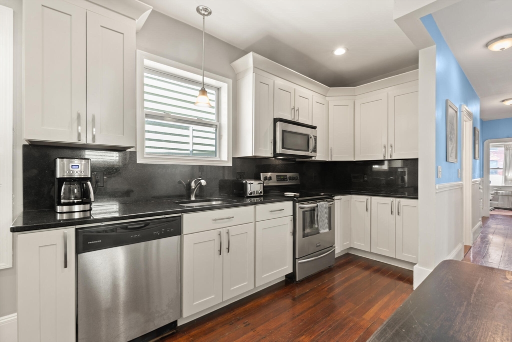 573 Bennington Street, Unit 2 Boston, MA 02128 - Photo 12 of 22 a kitchen with stainless steel appliances granite countertop white cabinets a sink a window and a refrigerator