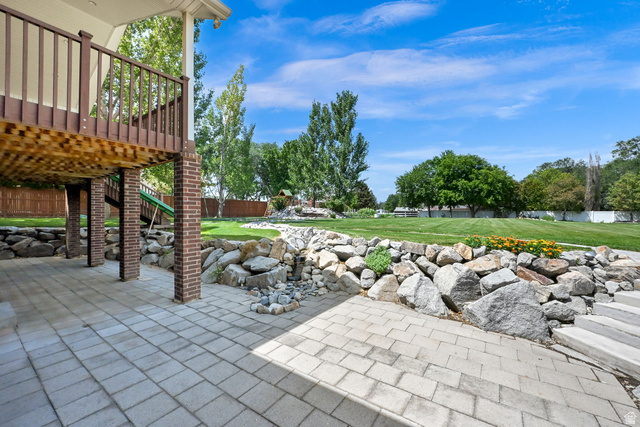 13658 South Fort Street Draper, UT 84020 - Photo 62 of 87 Expansive paver patio with a terraced rock wall and a large lawn area