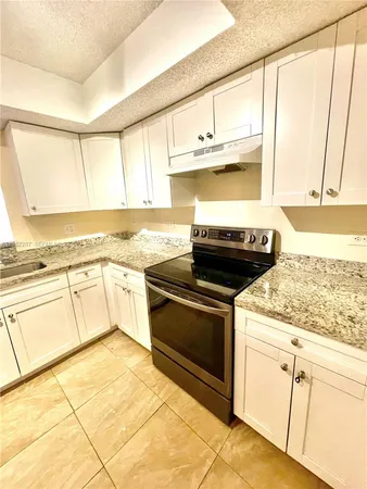 a kitchen with granite countertop a stove a sink and a microwave