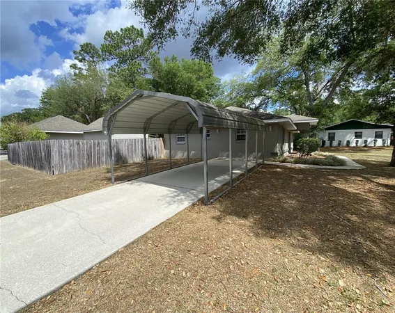 a backyard of a house with table and chairs under an umbrella