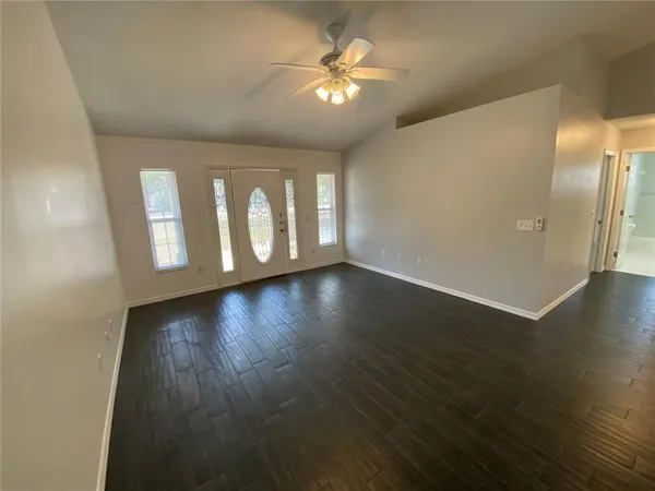 a view of an empty room with window and wooden floor
