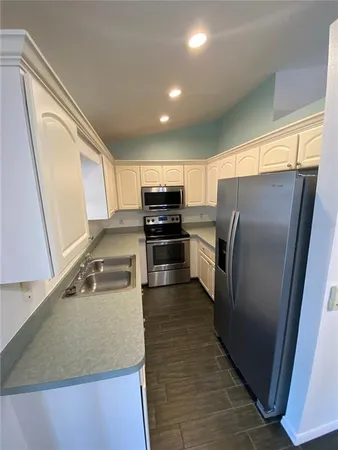 a kitchen with stainless steel appliances granite countertop a refrigerator a stove and a sink