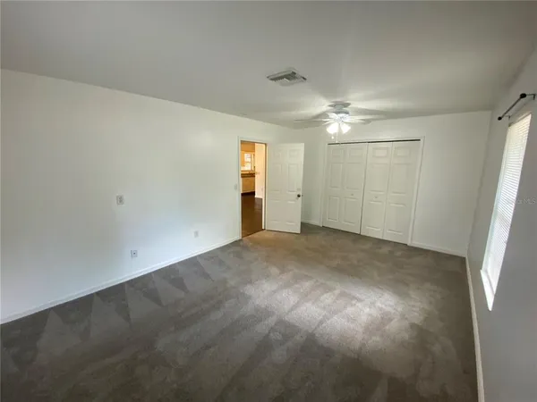 an empty room with a ceiling fan and a window