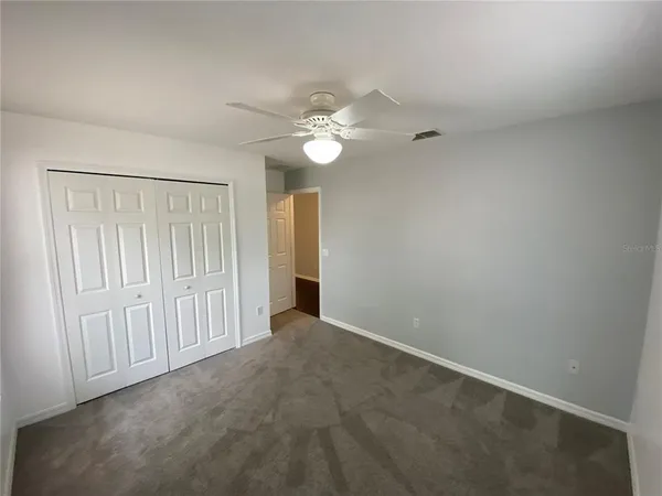 an empty room with a fan & a ceiling fan