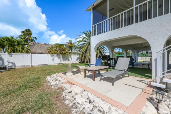 a view of a patio with table and chairs with plants and wooden fence