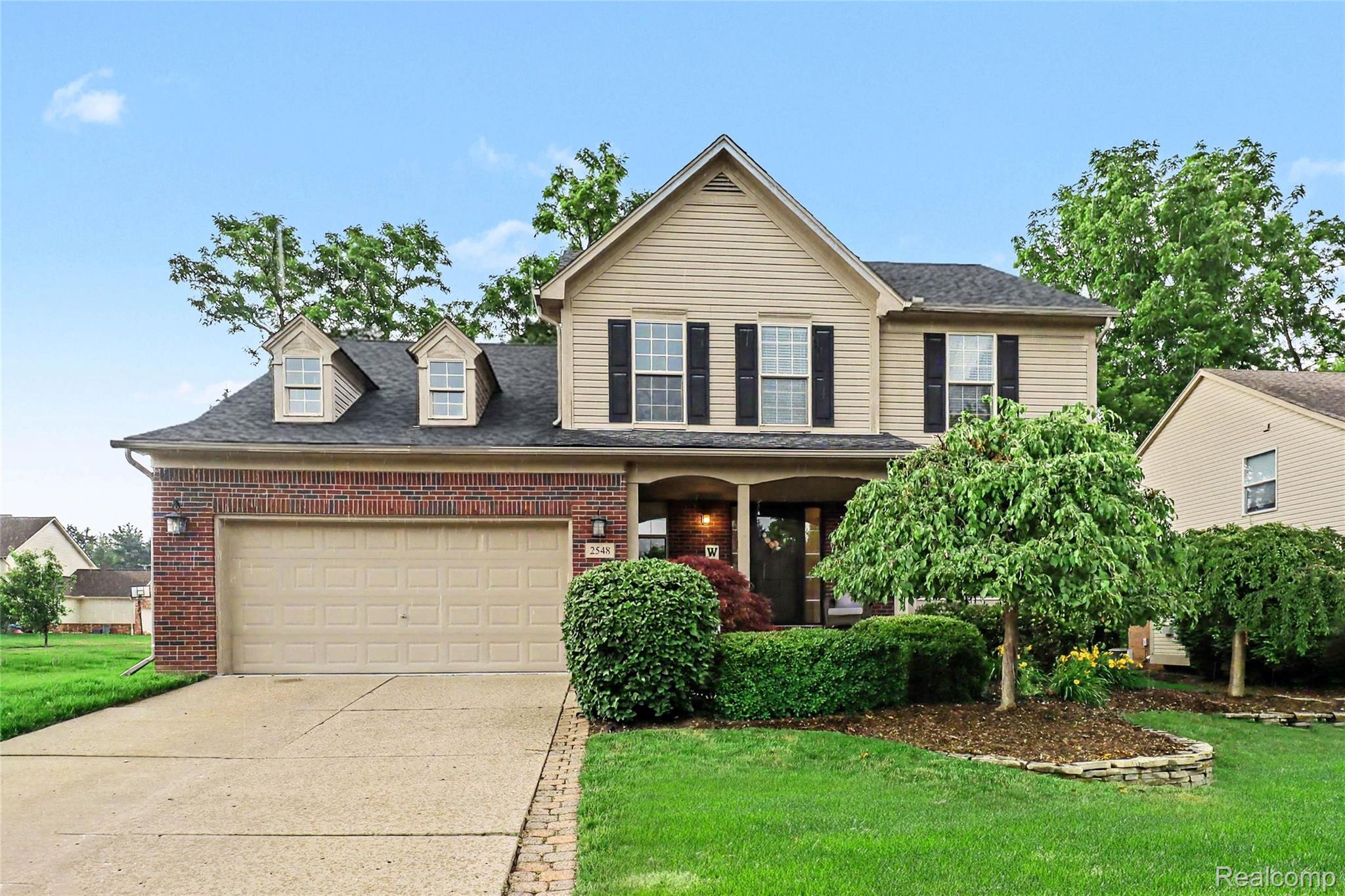 2548 Empire Court Rochester, MI 48309 - Photo 1 of 40 Two-story residence featuring brick and siding exterior, a two-car garage with overhead door, and a covered front porch