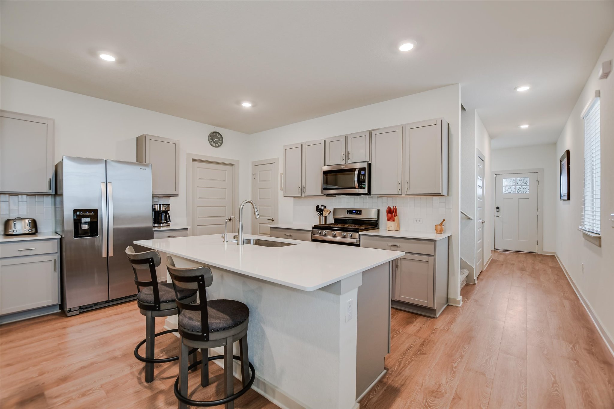 105 Merrick Road Georgetown, TX 78628 - Photo 2 of 23 A contemporary kitchen boasts a spacious island with a breakfast bar, complemented by stainless steel appliances and light wood flooring.