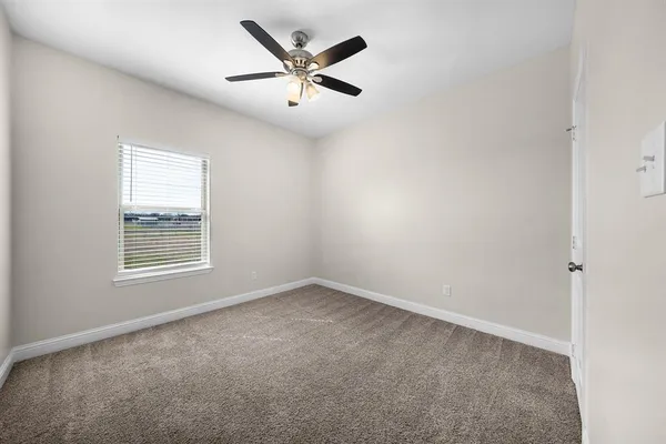 an empty room with a window and a fan