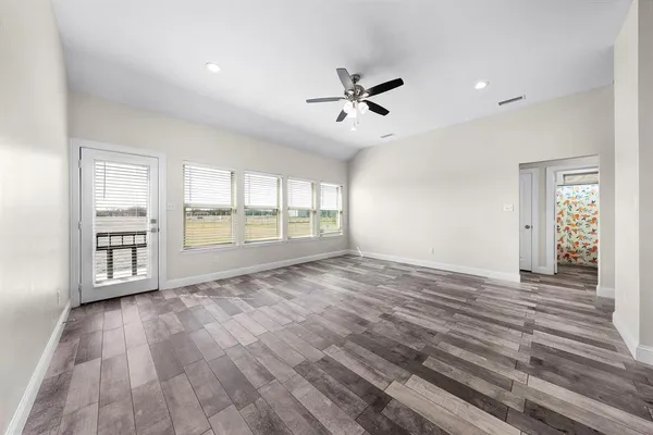 a view of an empty room with a window and wooden floor