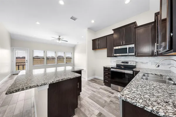 a kitchen with stainless steel appliances granite countertop a sink stove microwave and refrigerator