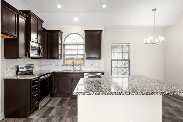 a kitchen with granite countertop stainless steel appliances a sink stove and cabinets