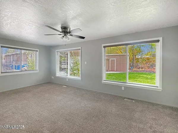 a view of an empty room with windows and chandelier fan