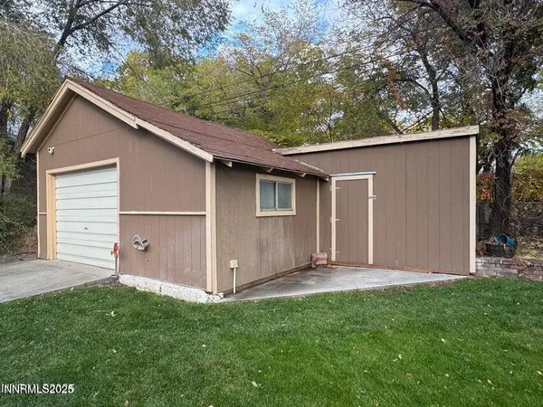 a backyard of a house with lawn chairs and a large tree