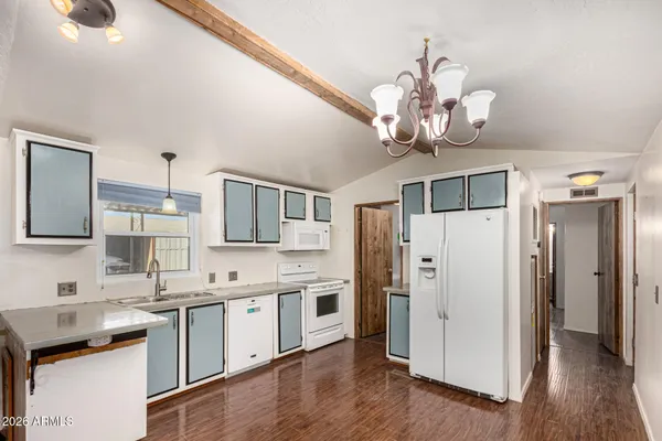 a kitchen with stainless steel appliances granite countertop a refrigerator a sink dishwasher and white cabinets with wooden floor