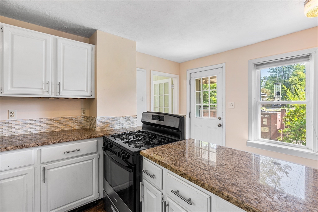 13 Maple Street Easthampton, MA 01027 - Photo 10 of 36 a kitchen with granite countertop a stove a sink dishwasher and white cabinets with wooden floor
