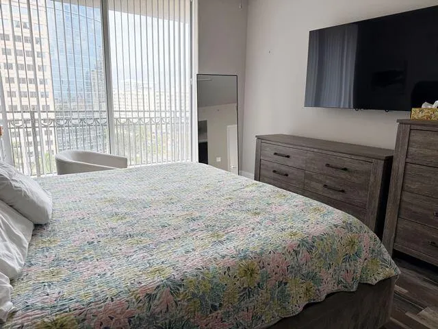 a bedroom with a bed and a flat tv screen on dresser