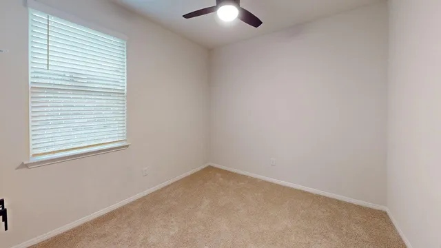 an empty room with a window and a fan