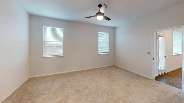 an empty room with windows and fan