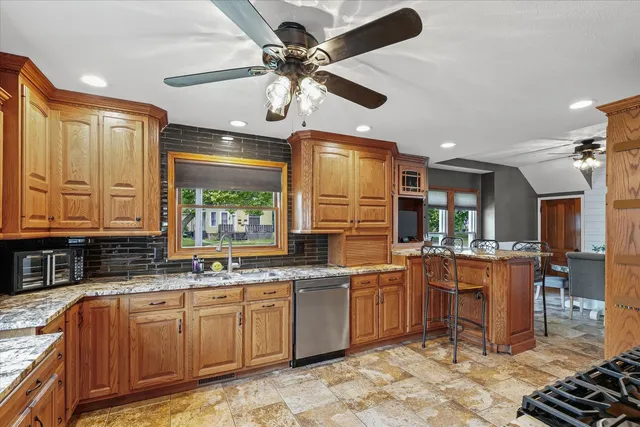 a kitchen with stainless steel appliances granite countertop a stove refrigerator a sink dishwasher a dining table and chairs with wooden floor