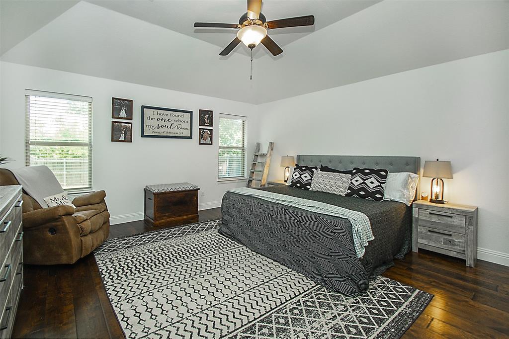 5809 Yellow Rose Court Midlothian, TX 76065 - Photo 12 of 33 Spacious bedroom featuring vaulted ceilings, dark wood-finish flooring, multiple windows with blinds, and a ceiling fan with integrated lighting
