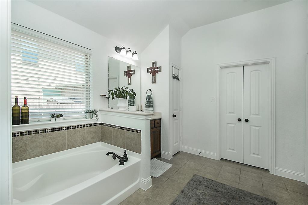 5809 Yellow Rose Court Midlothian, TX 76065 - Photo 13 of 33 White soaking tub with tiled surround, a large window with blinds, and tile flooring