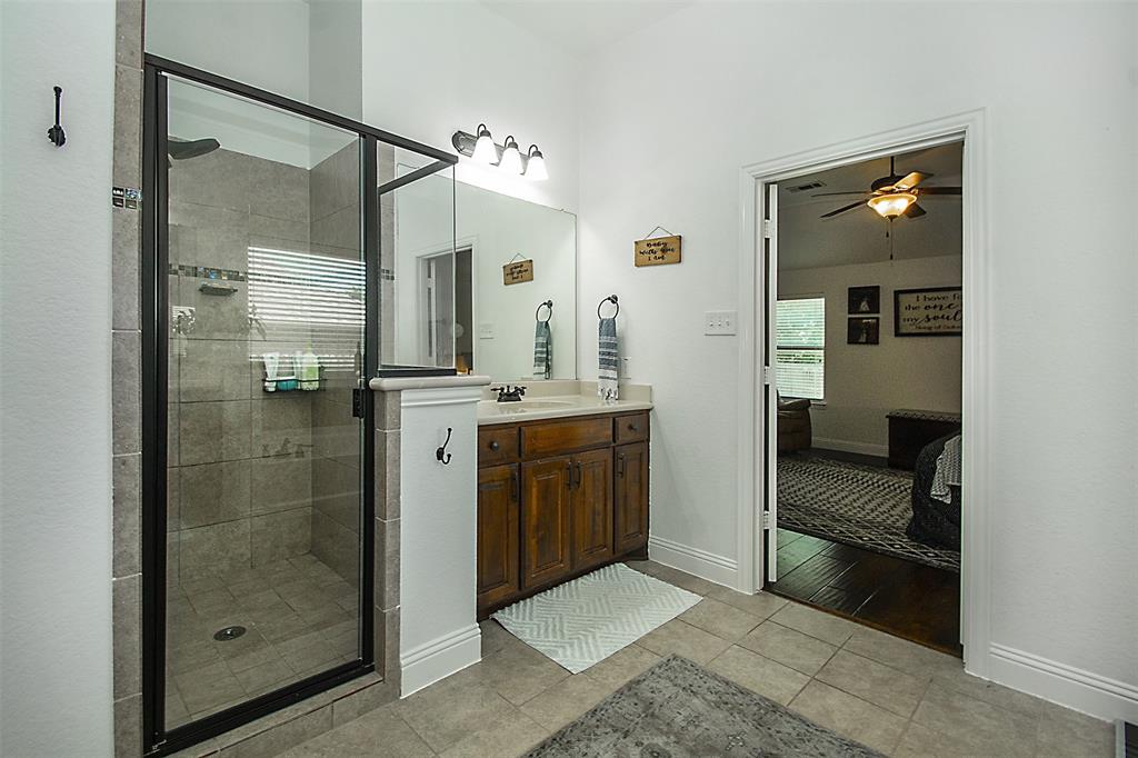 5809 Yellow Rose Court Midlothian, TX 76065 - Photo 14 of 33 Tiled shower with glass enclosure and a separate vanity featuring an integrated sink, wood-finish cabinetry, and a framed mirror