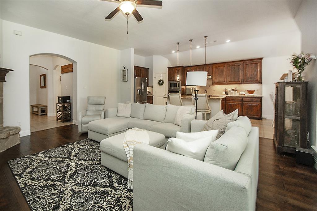 5809 Yellow Rose Court Midlothian, TX 76065 - Photo 16 of 33 Spacious living area featuring dark wood-finish flooring, a ceiling fan, and a stone fireplace hearth