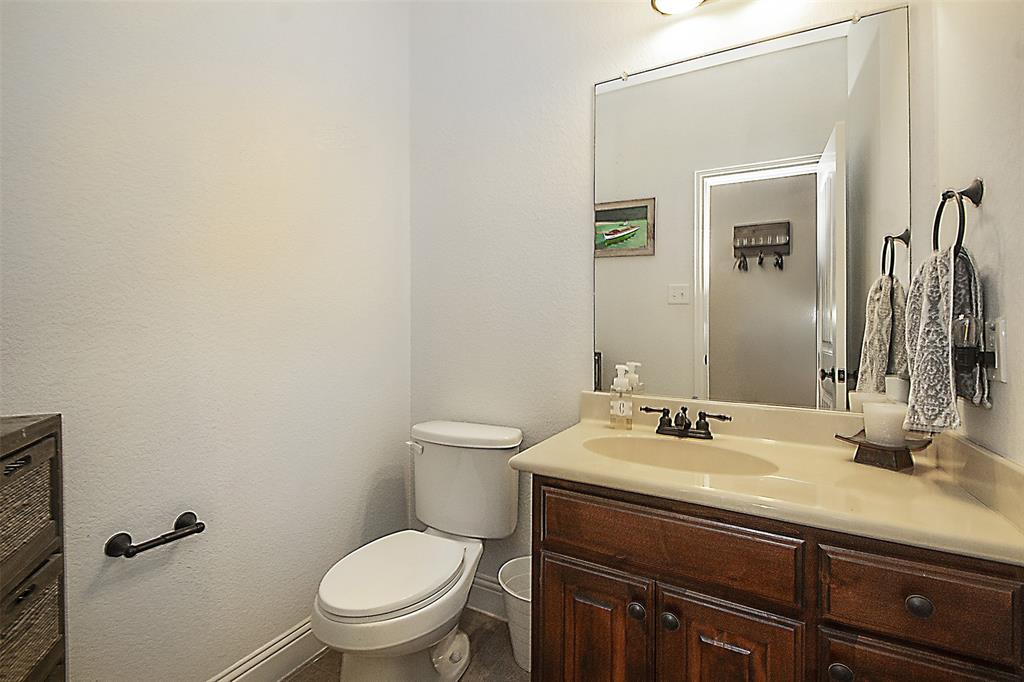 5809 Yellow Rose Court Midlothian, TX 76065 - Photo 21 of 33 Vanity featuring a light countertop, integrated sink, and dark wood-finish cabinetry with bronze hardware