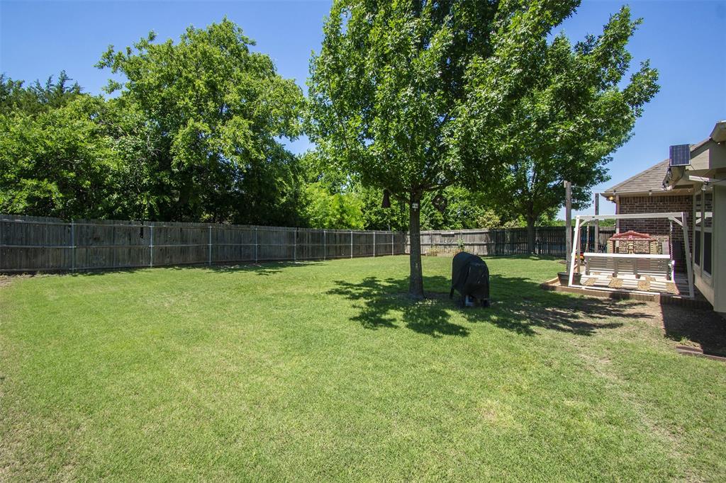 5809 Yellow Rose Court Midlothian, TX 76065 - Photo 25 of 33 Spacious fenced backyard featuring a manicured lawn, mature trees, and a concrete patio with a swing set