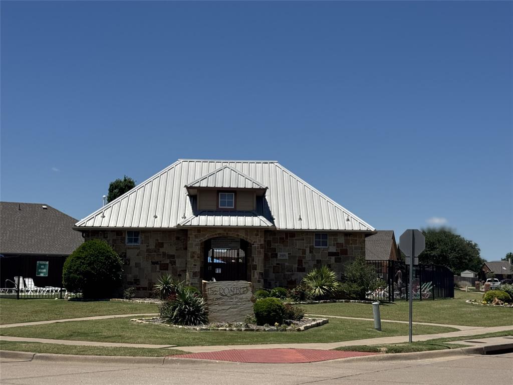 5809 Yellow Rose Court Midlothian, TX 76065 - Photo 31 of 33 Stone facade building with a metal standing seam roof, featuring an arched entryway and a dormer window