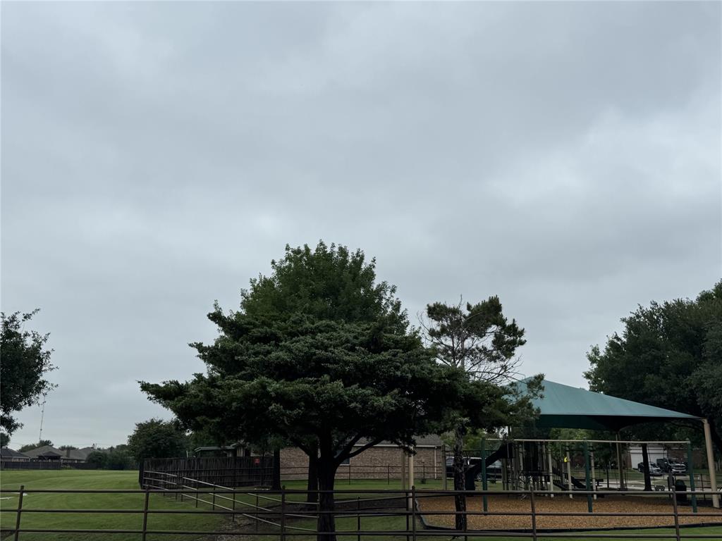 5809 Yellow Rose Court Midlothian, TX 76065 - Photo 32 of 33 Expansive outdoor space featuring a large grassy area, mature trees, a fenced perimeter, and a shaded play structure with a protective canopy