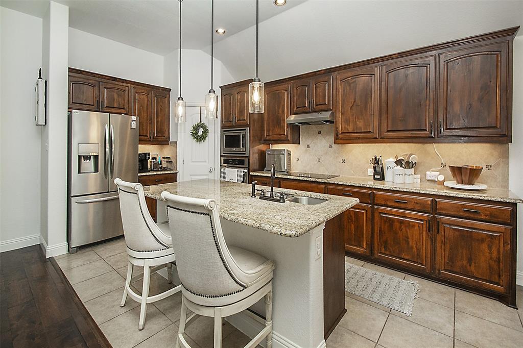 5809 Yellow Rose Court Midlothian, TX 76065 - Photo 9 of 33 Kitchen featuring a central island with a double basin sink, dark wood cabinetry, stainless steel appliances, pendant lighting, and tile flooring