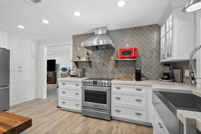 a kitchen with granite countertop a refrigerator a stove and a wooden floors
